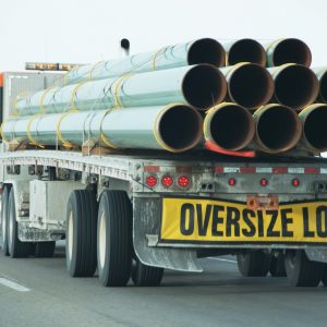 Oversize Load sign on back of truck carrying steel or fiberglass pipes Mexicom Logistics